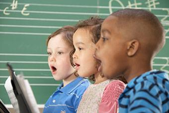 Children singing from sheet music.